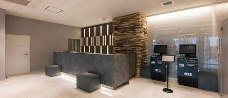 A reception area with a modern counter, a seating area, and a self-service kiosk.