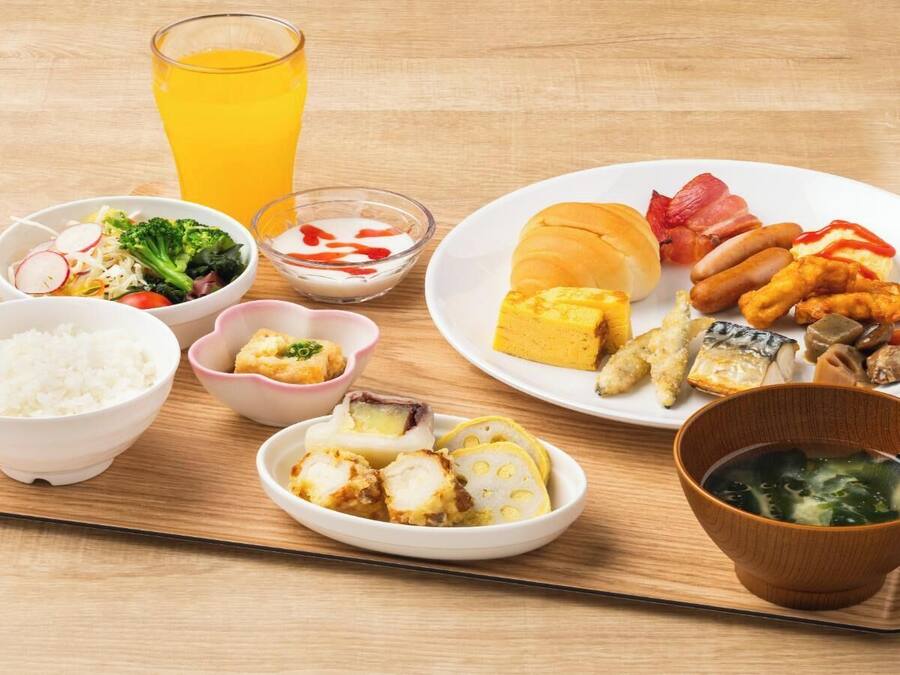 A meal with rice, vegetables, fish, and a drink on a wooden table.