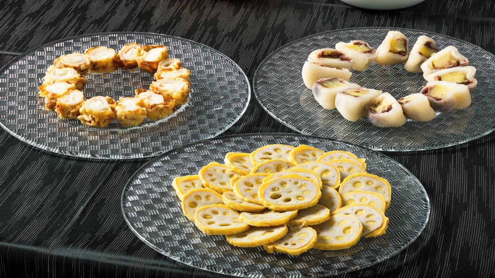 Drei Teller mit Essen auf einer strukturierten Tischdecke.