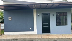 A modern house with a dark blue exterior, a white lower section, a black door, and a window with bars. - CORAL APARTMENT IN QUEPOS CLOSE TO MANUEL ANTONIO BEACH AND RESTAURANTS (Quepos)