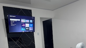 A hotel room with a bed, a TV mounted on the wall, and a door. - CORAL APARTMENT IN QUEPOS CLOSE TO MANUEL ANTONIO BEACH AND RESTAURANTS (Quepos)