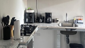 A compact kitchen with black cabinets, a microwave, a coffee maker, and a sink. - CORAL APARTMENT IN QUEPOS CLOSE TO MANUEL ANTONIO BEACH AND RESTAURANTS (Quepos)