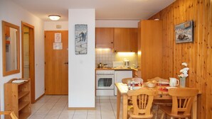 Eine kompakte Küche mit Holzausstattung, einem Esstisch mit Stühlen und einem kleinen Backofen.