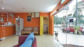Ein Empfangsbereich mit einer Couch, einer Rezeption mit Kühlschrank und einer Glastür zum Außenbereich.