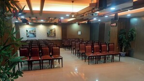 Un salón de conferencias con filas de sillas de madera, piso pulido e iluminación empotrada en el techo.