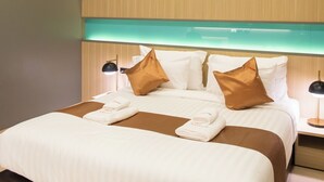 A modern hotel room with a large bed, two bedside tables, and a headboard with built-in lighting. - River Hotel Hatyai (Hat Yai)