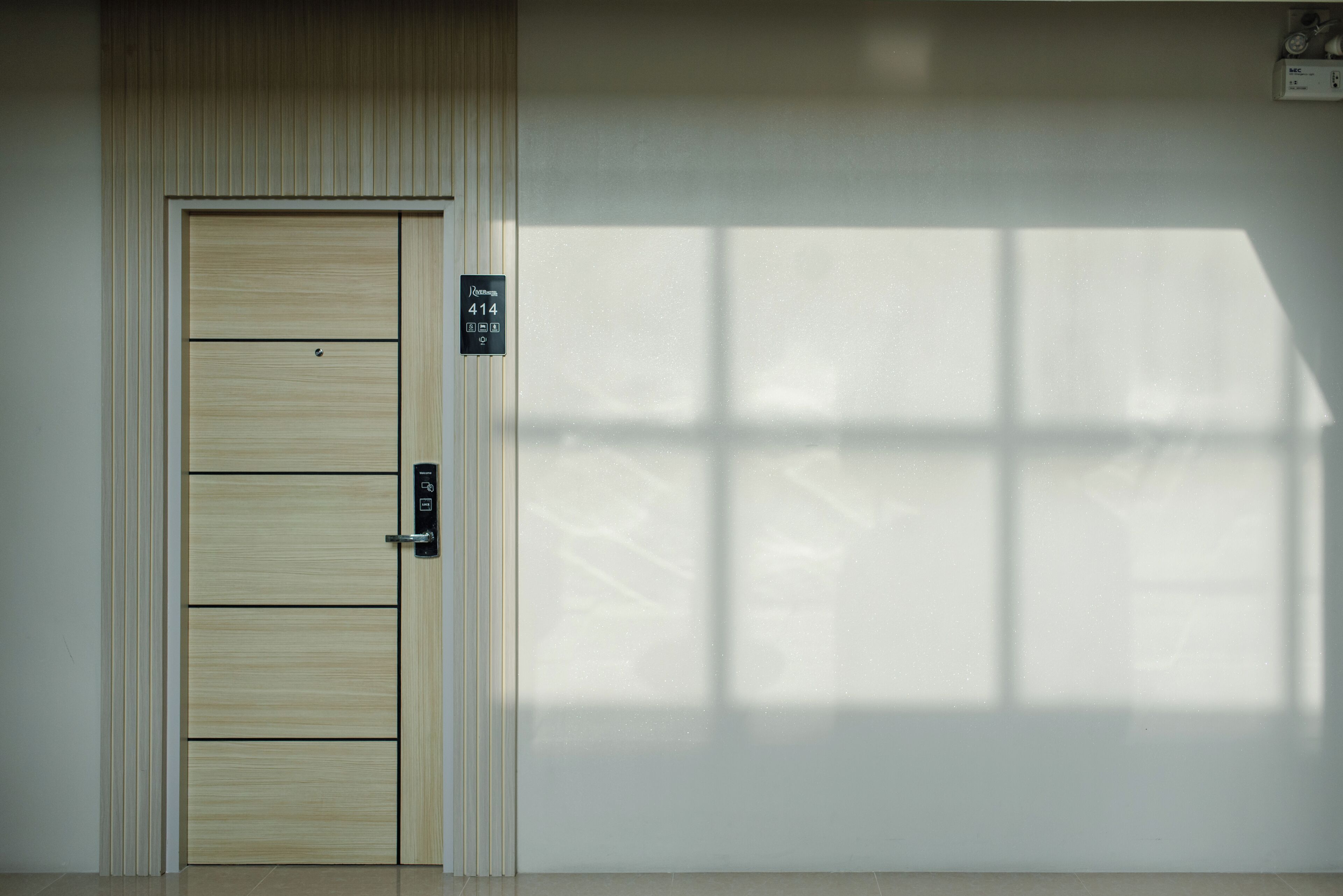 A door with a panel design, a sign indicating room number 414, and a shadow pattern on the wall.