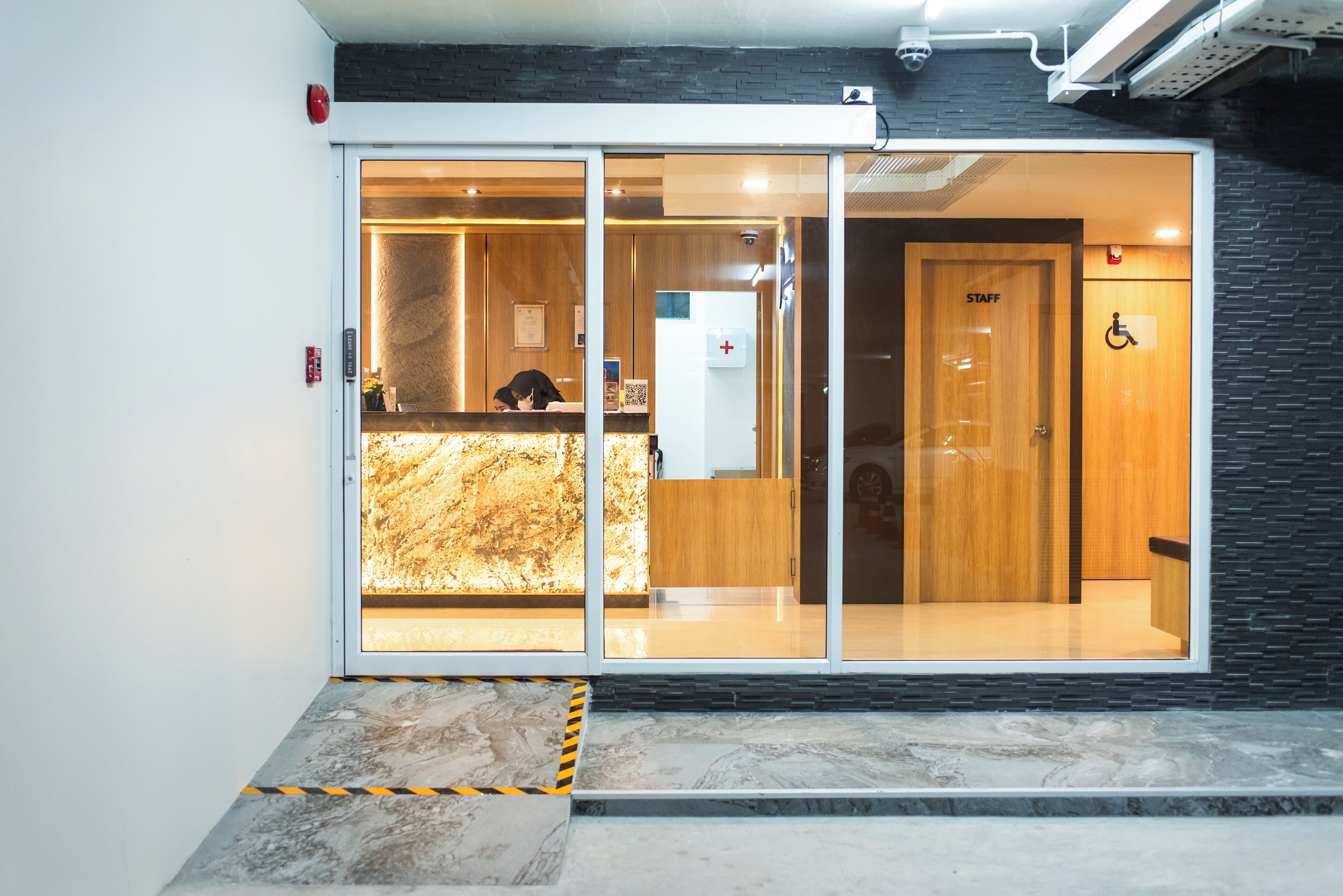 A hotel reception area with a marble floor, a reception desk, and a staff door.