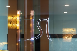 Un interior moderno con superficies reflectantes y señalización iluminada.