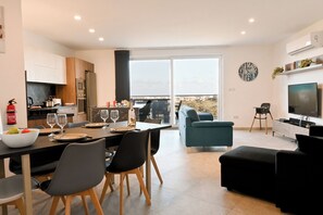 Eine moderne Küche mit Essbereich, ein Wohnzimmer mit Fernseher und ein Balkon mit Blick auf die Stadt.