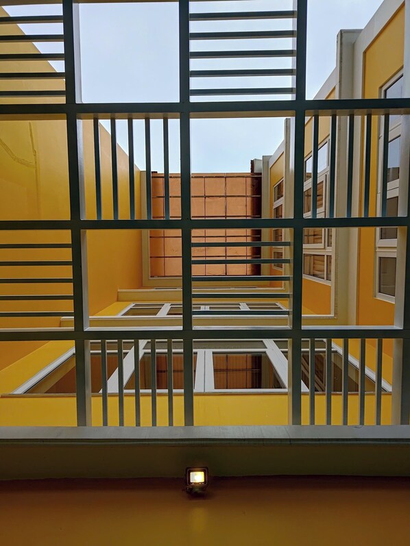 A yellow building with a barred window, a small light fixture, and a staircase. - Horizon Hotel by LunaVerde Hoi An (Thanh pho Hoi An)