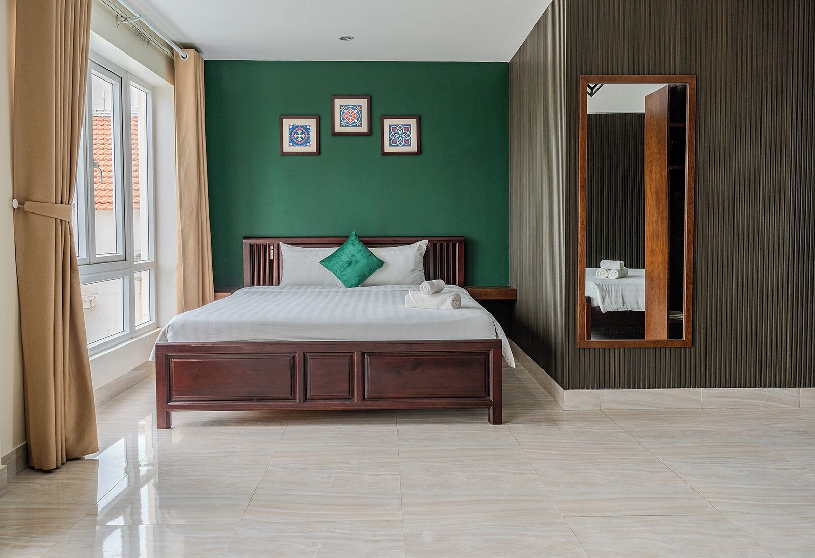 A hotel room with a large bed, a mirror, and three framed pictures on the wall.
