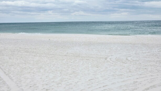 A beach with a sandy shore and a calm sea under a cloudy sky. - Lani kai unit 111. Cozy 2bed-2bath condo with beach access. PRIME LOCATION (Gulf Shores)