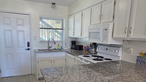 A kitchen with white cabinets, a granite countertop, a stove, and a trash bin. - Lani kai unit 111. Cozy 2bed-2bath condo with beach access. PRIME LOCATION (Gulf Shores)