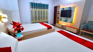 A hotel room with two beds, a TV, a sofa, and a decorative wall.