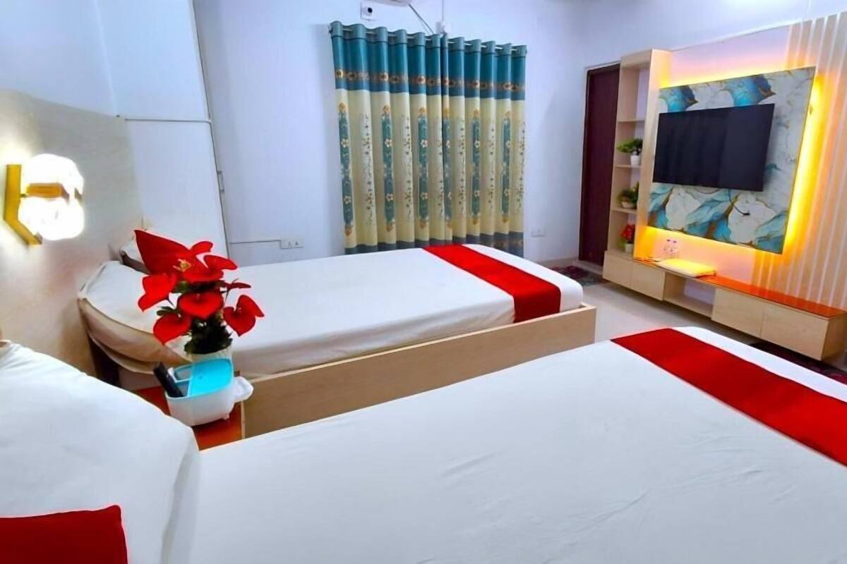 Ett hotellrum med två sängar, en TV, en soffa och en dekorativ vägg.
