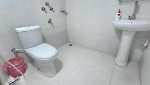 A bathroom with a toilet, a sink, and a showerhead.