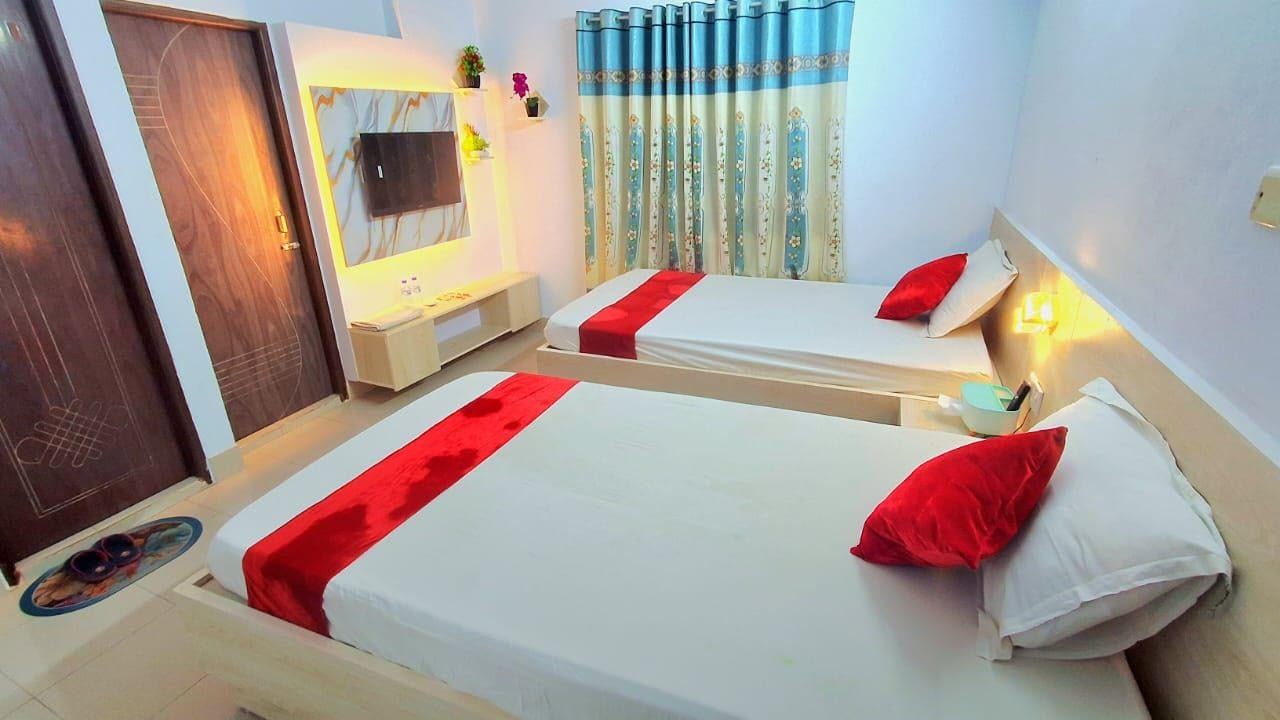 A hotel room with two beds, a television, a small table, and a curtain.