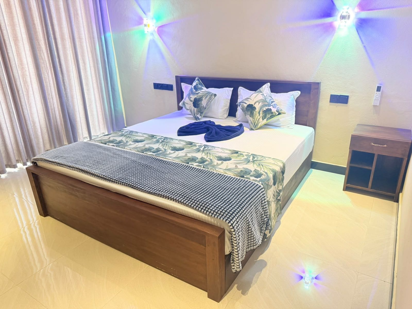 A hotel room with a bed, a bedside table, and a nightstand.
