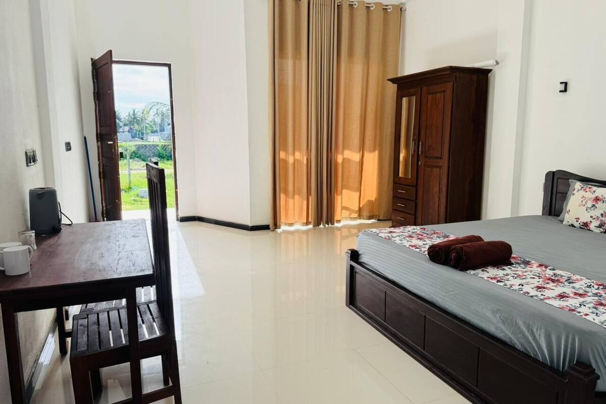 A bedroom with a bed, a wooden desk, and a view of the outdoors.