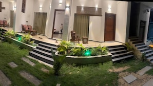 Entrada de un hotel con escaleras, zona de estar y un pequeño jardín.