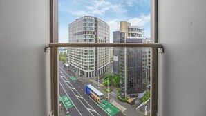 A view of a cityscape through a window, featuring a bus lane and a building with a sign that reads "CORDIS". - CBD 2-Bedroom Apt near Hospital and K`Rd (Auckland CBD)
