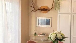 Un coin repas avec une table dressée pour quatre personnes, un vase de fleurs, une paire de bois de cerf accrochée au mur et un tableau encadré au-dessus de la table.