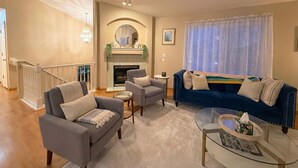 Un salon avec une cheminée, deux canapés, une table basse et un escalier.