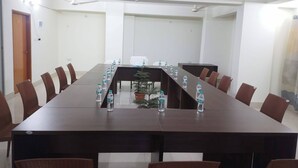 Un salón de conferencias con una mesa larga, sillas y botellas de agua.