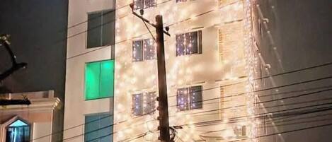 A multi-story hotel with illuminated windows and a sign reading "HOTEL BOGURA TODAY".