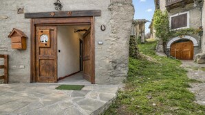 Un bâtiment rustique en pierre, doté d’une porte en bois, d’un petit nichoir en bois et d’un chemin en pierre.