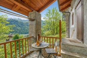 A balcony with a table set for two, a bottle, and glasses, overlooking a mountainous landscape. - Luna Apartment Baita Ayana With Balcony Views (Oulx)