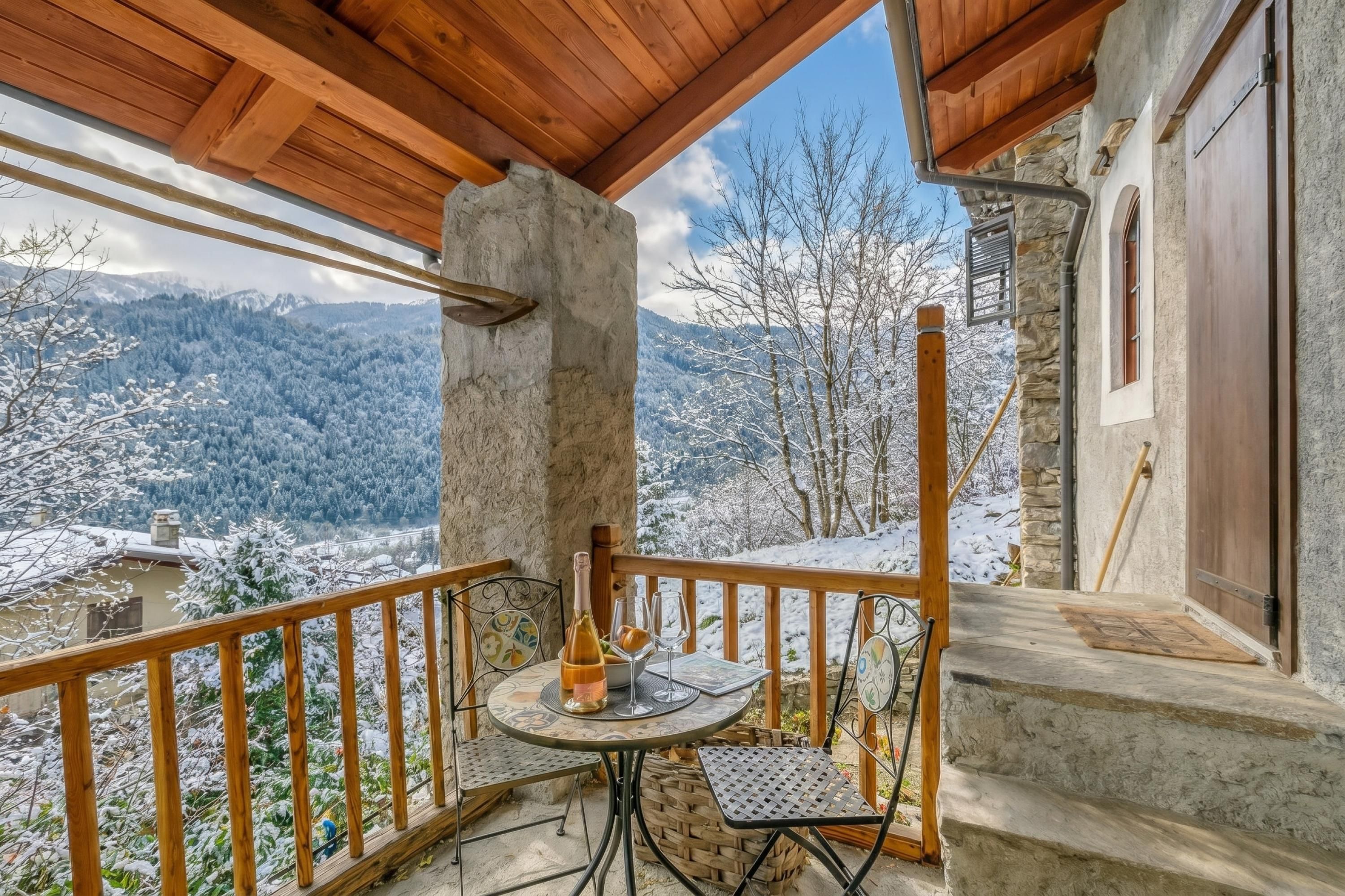 A balcony with a table and chairs, overlooking a snowy mountainous landscape.