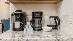 Une cuisine équipée d’une machine à café, d’une bouilloire et d’un porte-tasses avec des tasses.