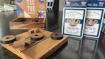 Un juego de tres en raya de madera, dos paquetes de cartas y una caja de naipes sobre una mesa.