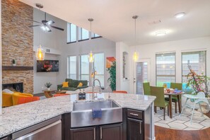 Una cocina moderna con encimera de granito, electrodomésticos integrados e iluminación colgante.