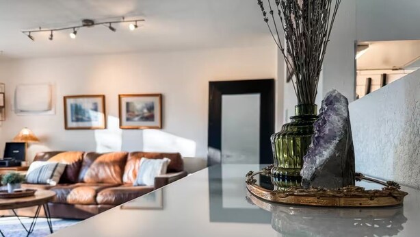 A modern living room with a leather sofa, a coffee table, and a decorative vase with a crystal on a reflective surface. - Clean, quiet, 2-bedroom South Hill rental with a Garage. Conveniently located. (Spokane)