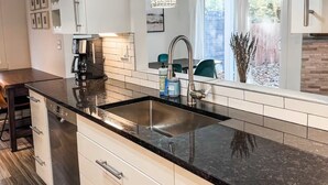A modern kitchen with a black countertop, stainless steel sink, and white cabinets. - Clean, quiet, 2-bedroom South Hill rental with a Garage. Conveniently located. (Spokane)