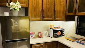 A kitchen with wooden cabinets, a stainless steel refrigerator, a microwave, and a coffee maker on the counter.