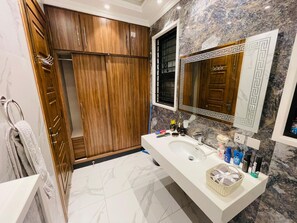 Ein Badezimmer mit Holzschrank, Marmorwaschbecken und Spiegel mit Zierrahmen.