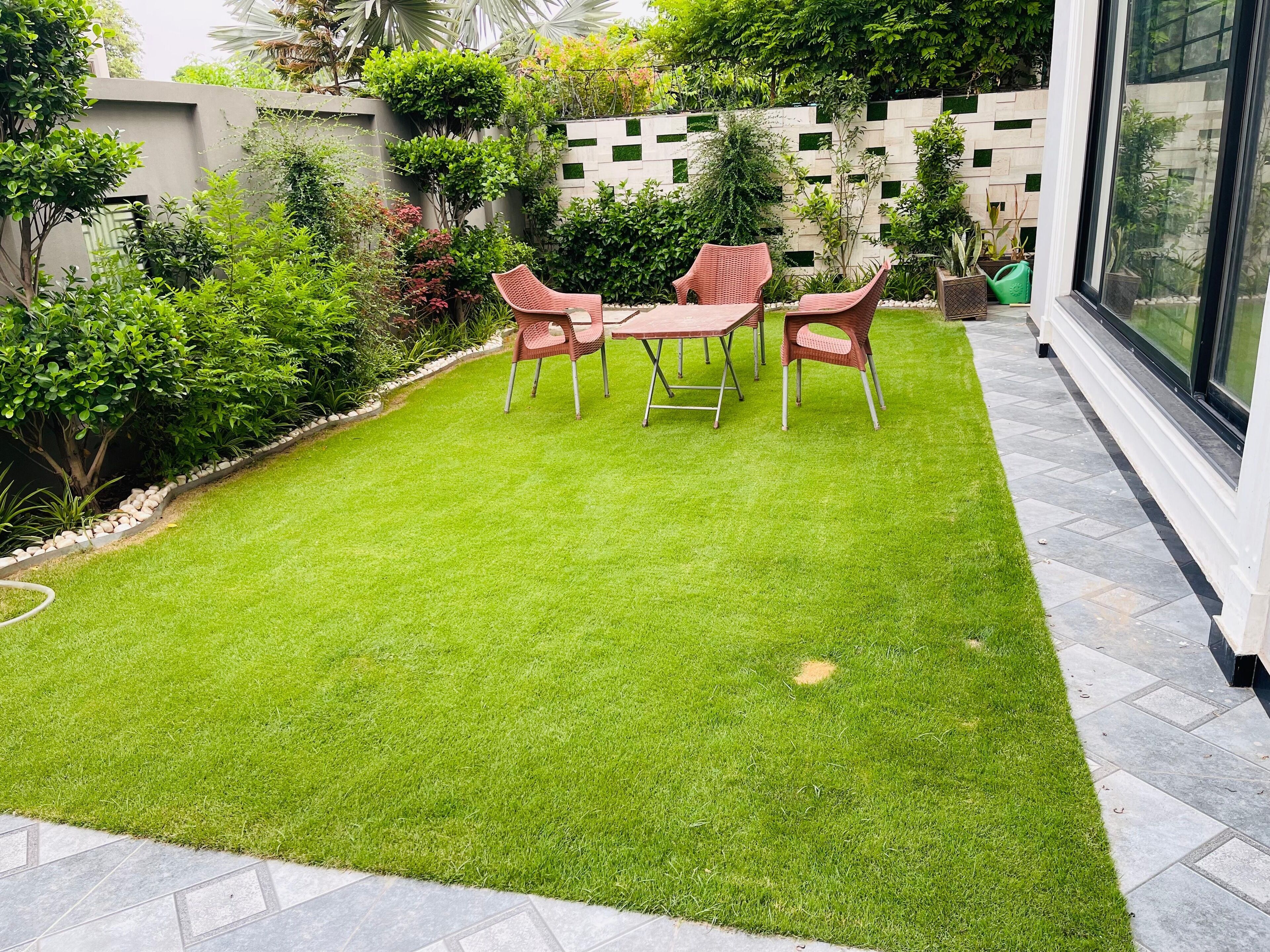 Un jardin bien entretenu, avec une pelouse, une table et quatre chaises.
