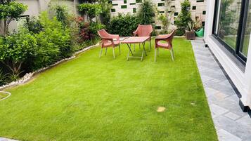 Un jardin bien entretenu, avec une pelouse, une table et quatre chaises.