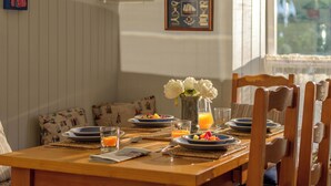 Une table à manger dressée avec des assiettes, des verres et un vase de fleurs.