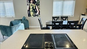 A kitchen with a central island, a dining table with chairs, and a blue sofa.