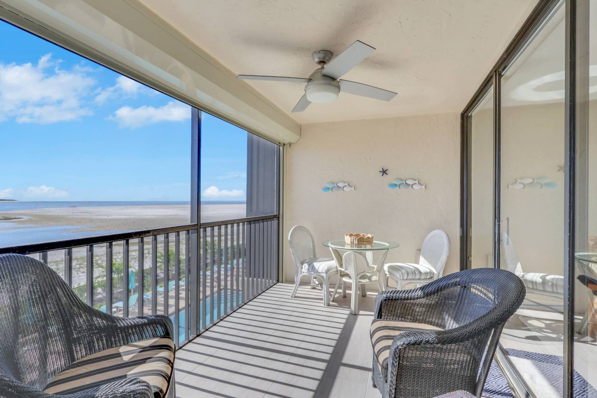 Ein Balkon mit Blick auf den Strand, Deckenventilator und ein Tisch mit Stühlen.