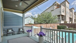 Une terrasse extérieure couverte avec une piscine, des meubles en osier et des plantes en pot.
