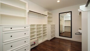 Un dressing accessible sans porte, doté d’étagères ouvertes, de tiroirs et d’une porte-miroir.