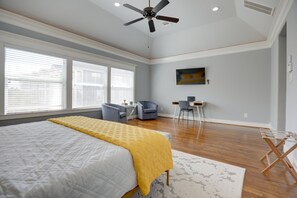 A bedroom with a bed, a ceiling fan, a desk with a chair, and a window with blinds. - Downtown Houston-Private Pool, Hot Tub & Game Room (Houston)