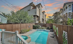 A residential backyard with a swimming pool, wooden fence, and string lights. - Downtown Houston-Private Pool, Hot Tub & Game Room (Houston)