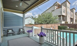 A covered outdoor deck with a pool, wicker furniture, and potted plants.
